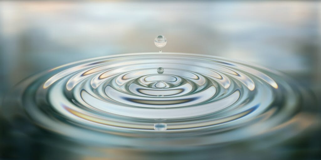 A drop of water falling into a large pool of water