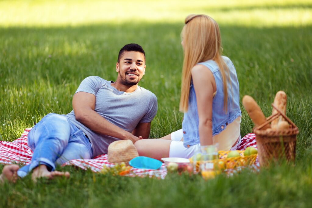 Couple sitting on a blanket in the grass having a picnic