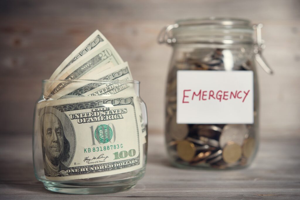 A stack of $100 bills and a jar filled with coins with 